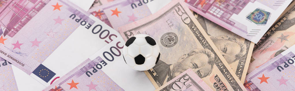 panoramiczny strzał piłki nożnej zabawki na banknotach dolarowych i euro, koncepcja zakładów sportowych - Zdjęcie, obraz