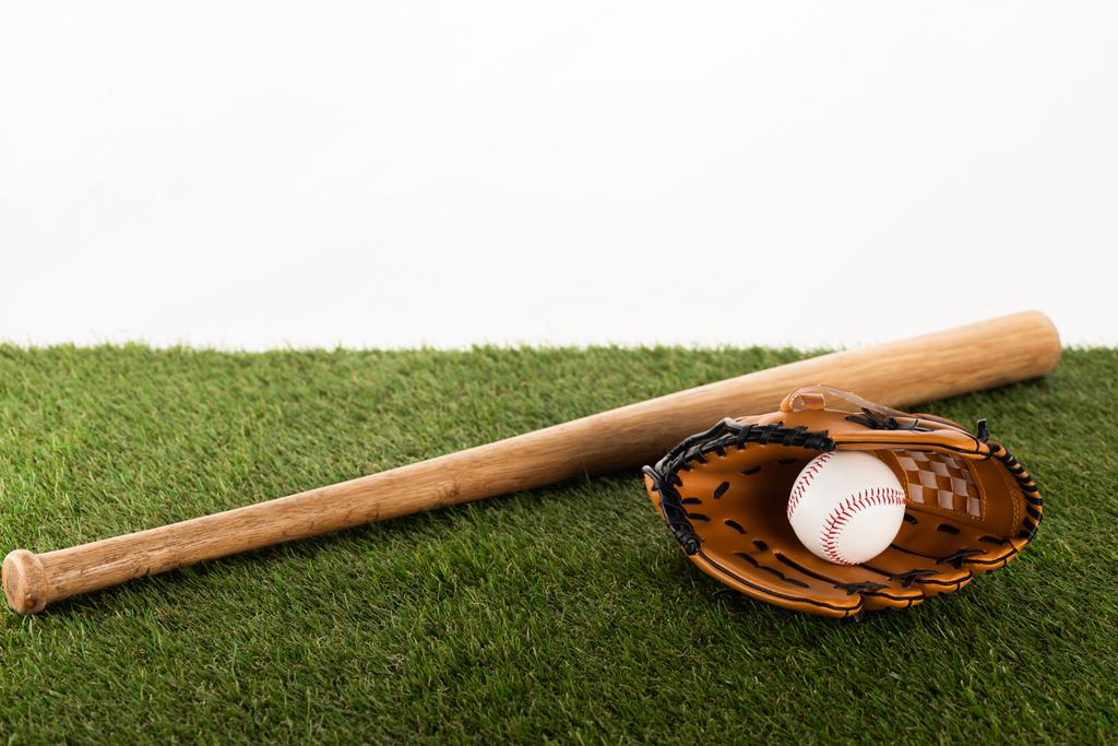бейсбольная бита, перчатка и мяч на зеленой траве, изолированные на белом, концепция спортивных ставок
 - Фото, изображение