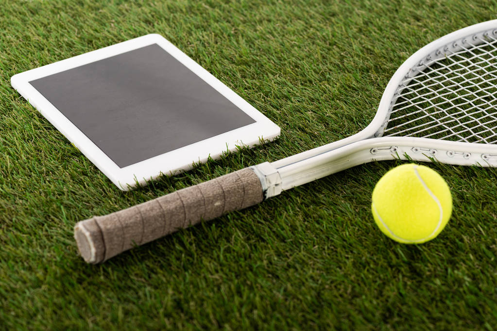 raqueta de tenis y pelota cerca de tableta digital con pantalla en blanco sobre hierba verde, concepto de apuestas deportivas
 - Foto, imagen