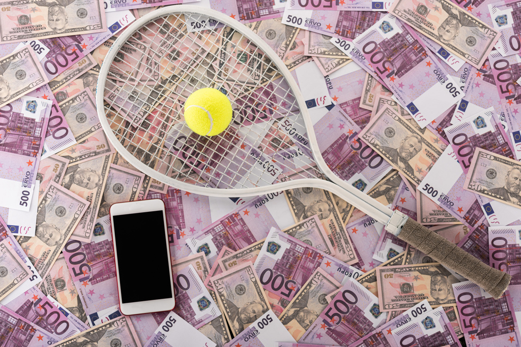shora pohled na smartphone s prázdnou obrazovkou, tenisovou raketou a míčkem na eurobankovky a dolarové bankovky, koncept sportovního sázení - Fotografie, Obrázek