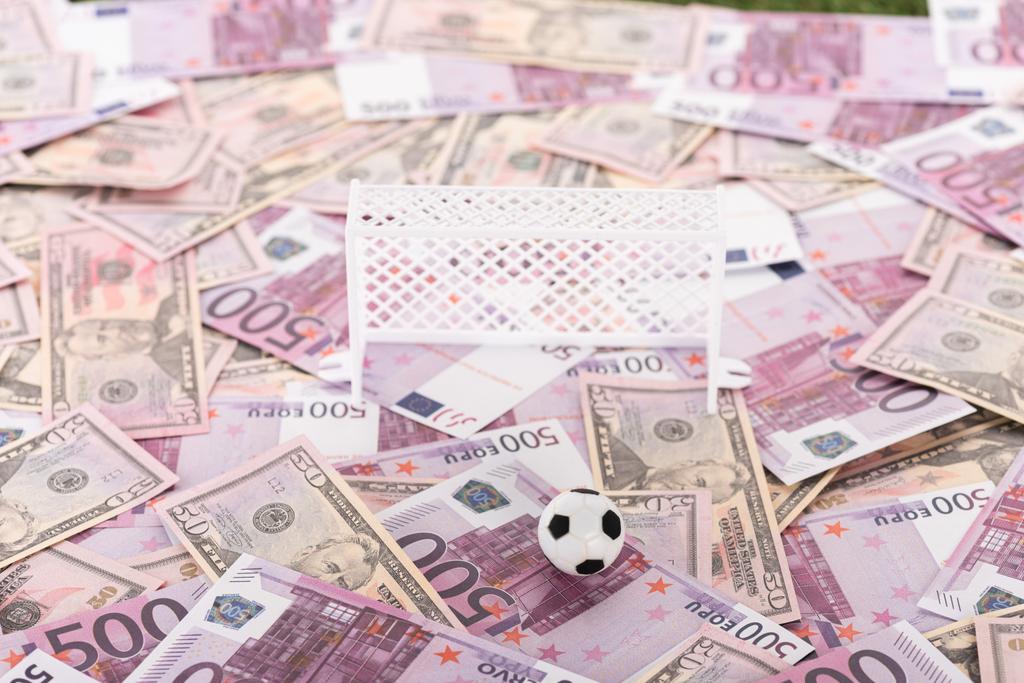 πύλες παιχνιδιού ποδοσφαίρου και μπάλα σε τραπεζογραμμάτια ευρώ και δολαρίου, έννοια αθλητικών στοιχημάτων - Φωτογραφία, εικόνα