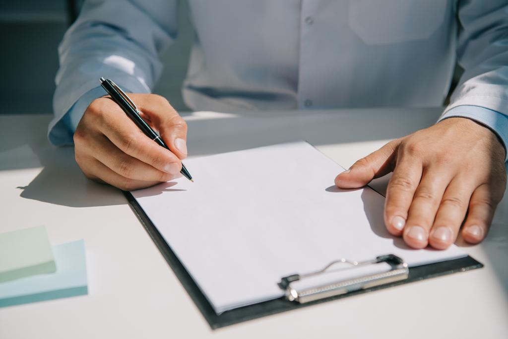 περικοπή άποψη του γιατρού κρατώντας στυλό κοντά στο πρόχειρο με λευκό χαρτί  - Φωτογραφία, εικόνα