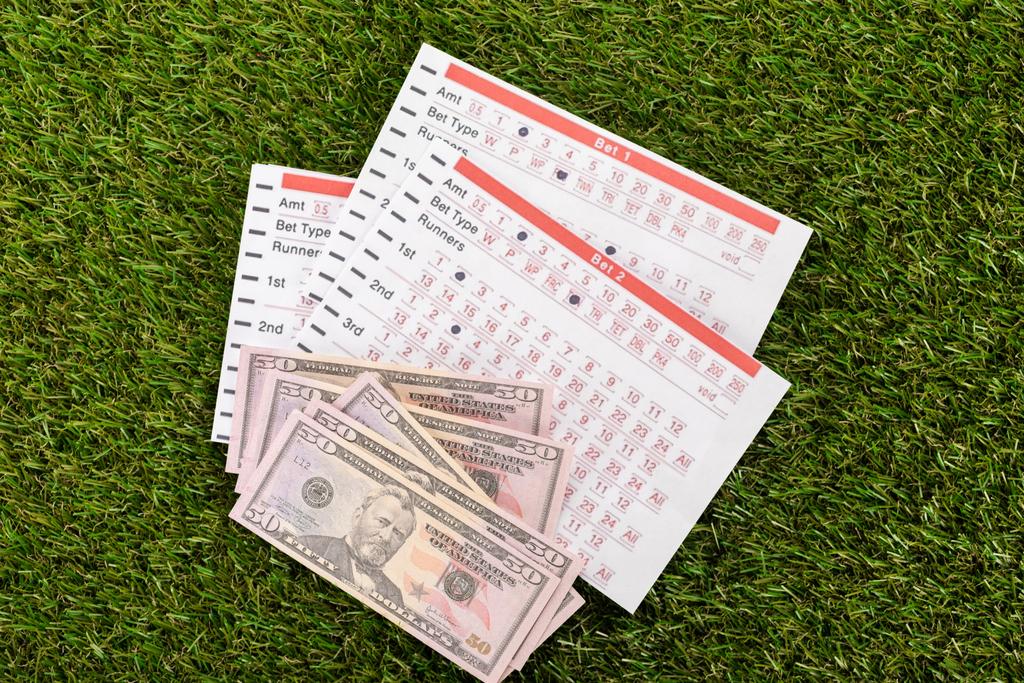 vista superior de billetes de dólar y listas de apuestas en hierba verde, concepto de apuestas deportivas
 - Foto, Imagen