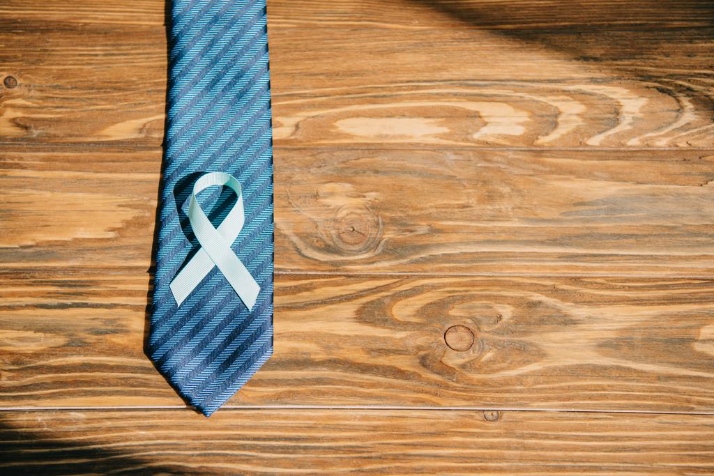 kravata a modrá informační stuha na dřevěném povrchu - Fotografie, Obrázek