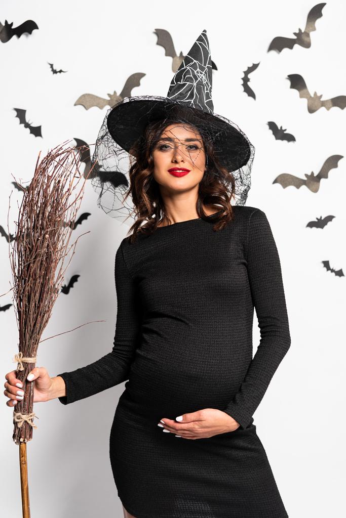 pregnant woman in witch hat holding broom in Halloween - Photo, Image