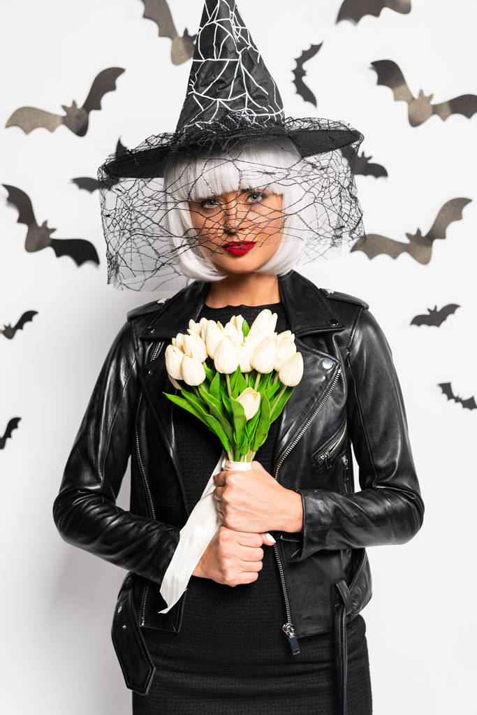 mulher atraente em chapéu de bruxa e peruca segurando buquê no Halloween
 - Foto, Imagem