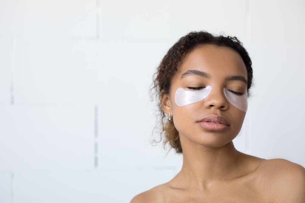 Giovane donna afro americana con rilievi di collagene sotto gli occhi su sfondo bianco
. - Foto, immagini
