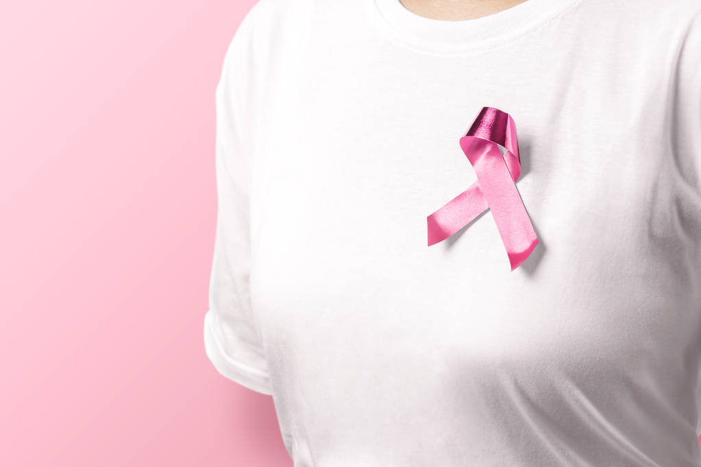 Frau in weißem Hemd mit rosa Schleife über rosa Hintergrund - Foto, Bild