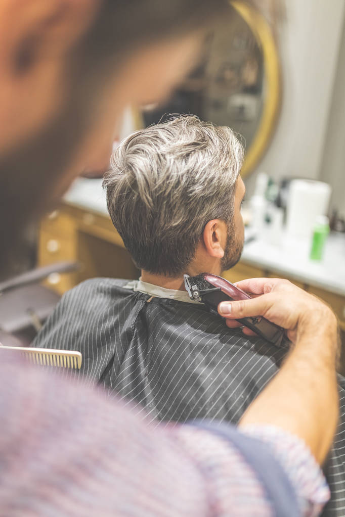 Un salon de coiffure. Coiffeur fait coiffure avec tondeuse à cheveux
. - Photo, image