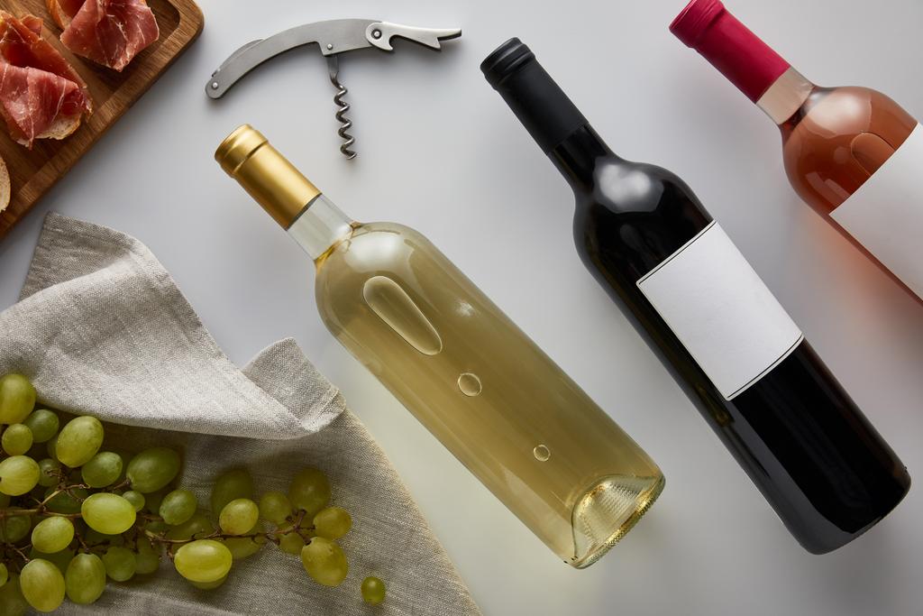 白・赤・ローズのワインをブドウ・コルク栓・スライスしたプロシュートに近い白を基調としたバゲットの上からの眺め - 写真・画像