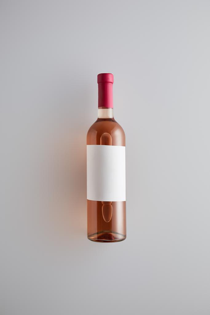 horní pohled na láhev s růžovým vínem a prázdný štítek na bílém pozadí - Fotografie, Obrázek