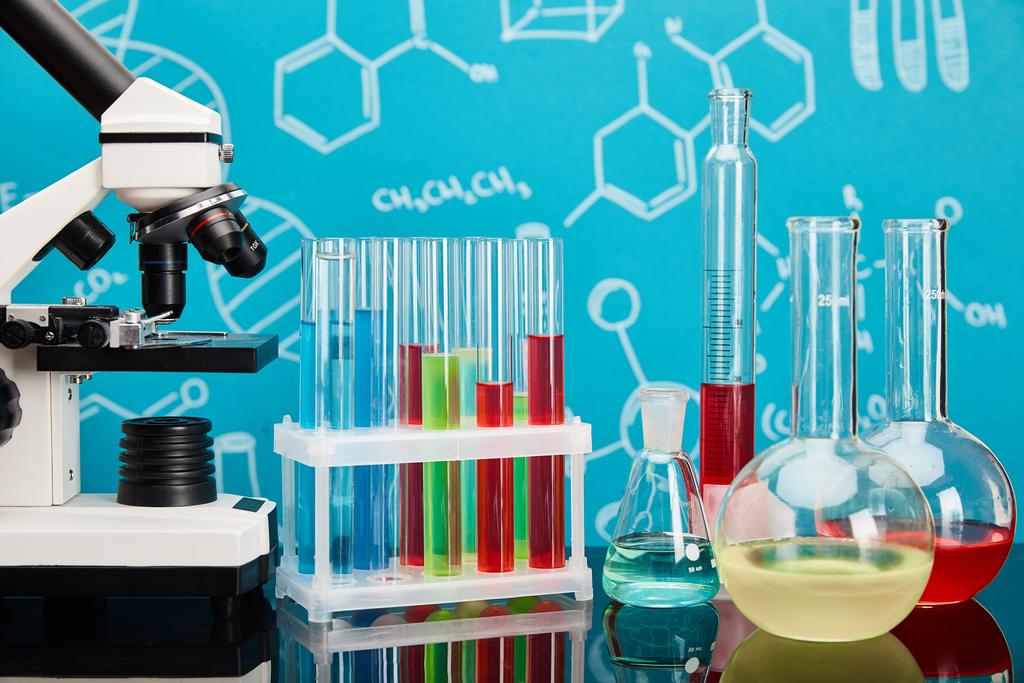 Mikroskop, Reagenzgläser und Kolben mit bunter Flüssigkeit auf blauem Hintergrund mit molekularer Struktur - Foto, Bild