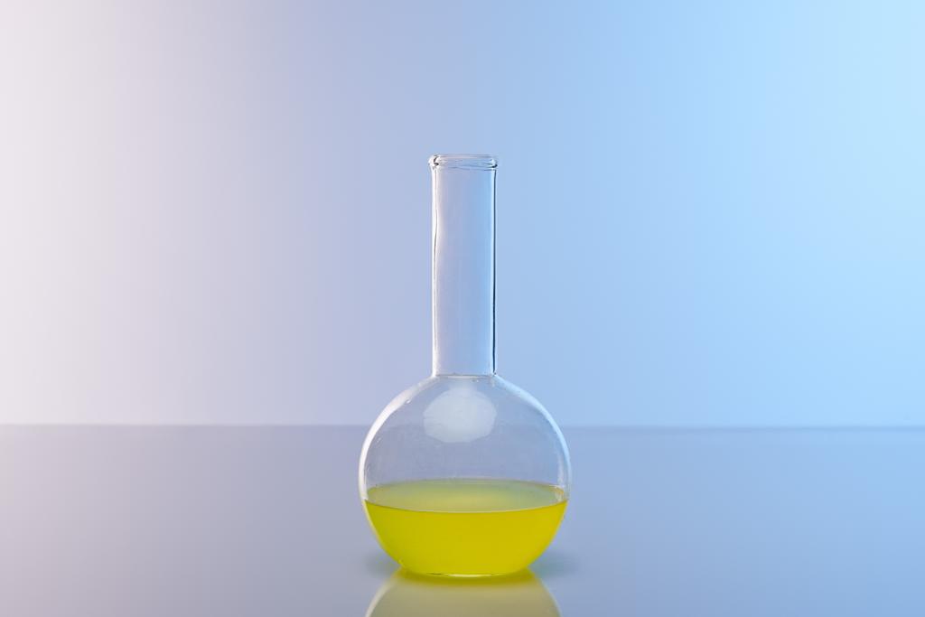 glazen kolf met kleurrijke gele vloeistof - Foto, afbeelding