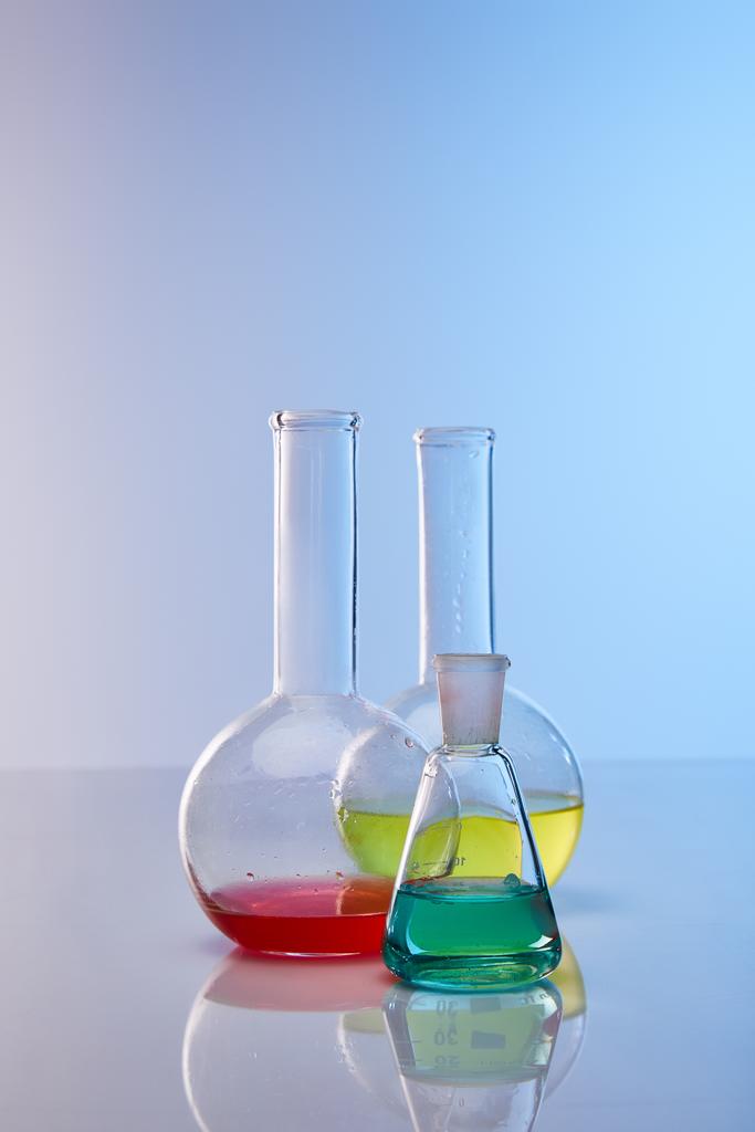 színes sárga, kék és piros folyadékot tartalmazó üveglombikok - Fotó, kép