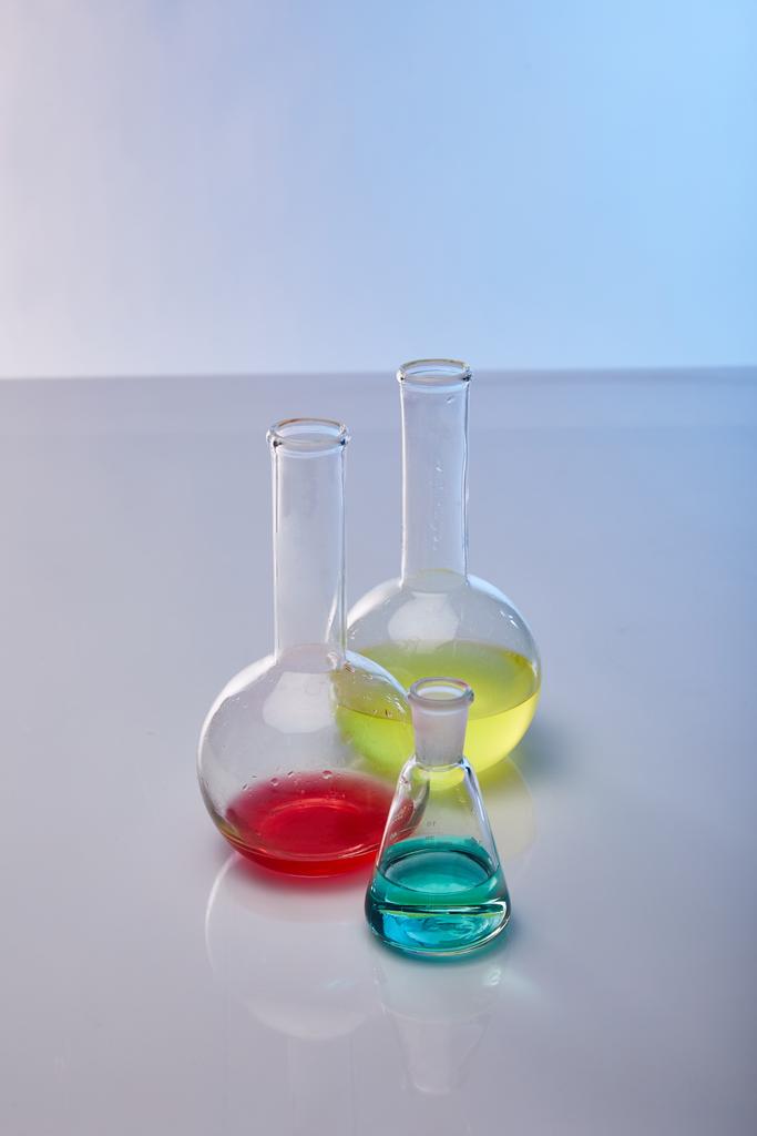 frascos de vidrio con colorido líquido amarillo, azul y rojo
 - Foto, Imagen