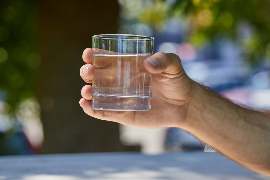 καλλιεργημένη άποψη του ανθρώπου κρατώντας γυαλί με καθαρό γλυκό νερό εξωτερική - Φωτογραφία, εικόνα