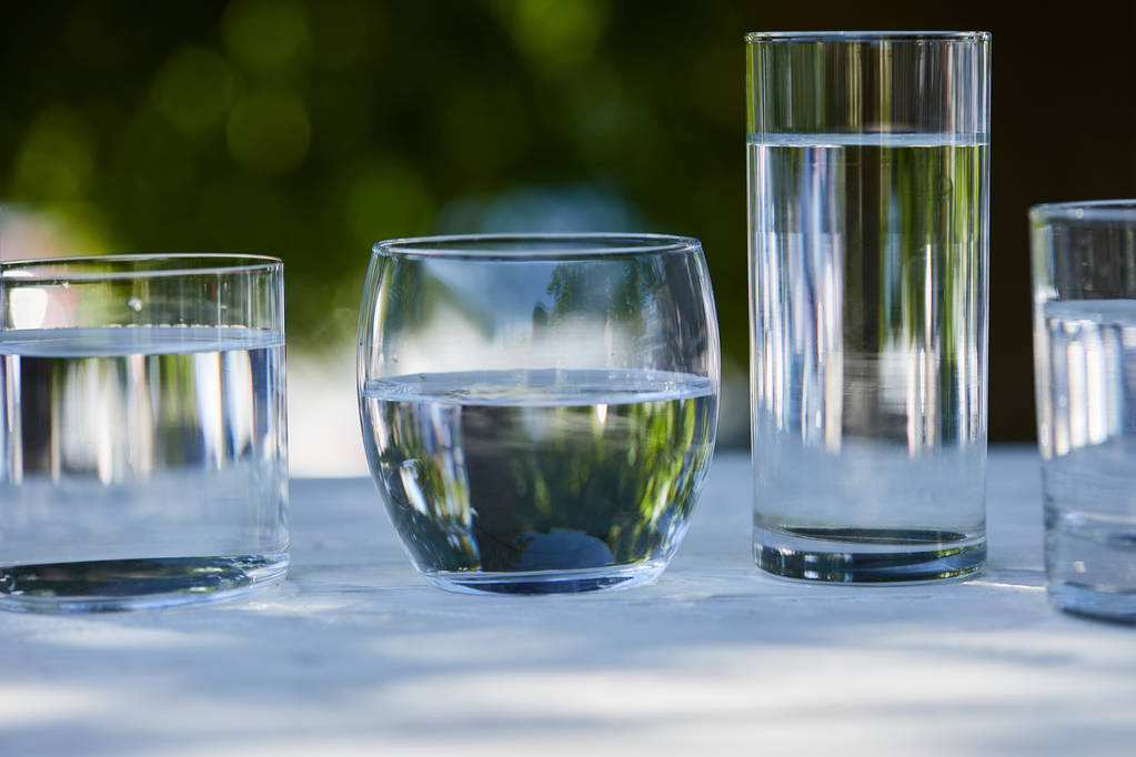 tiszta édesvíz átlátszó üvegben napfényben fából készült asztalon - Fotó, kép