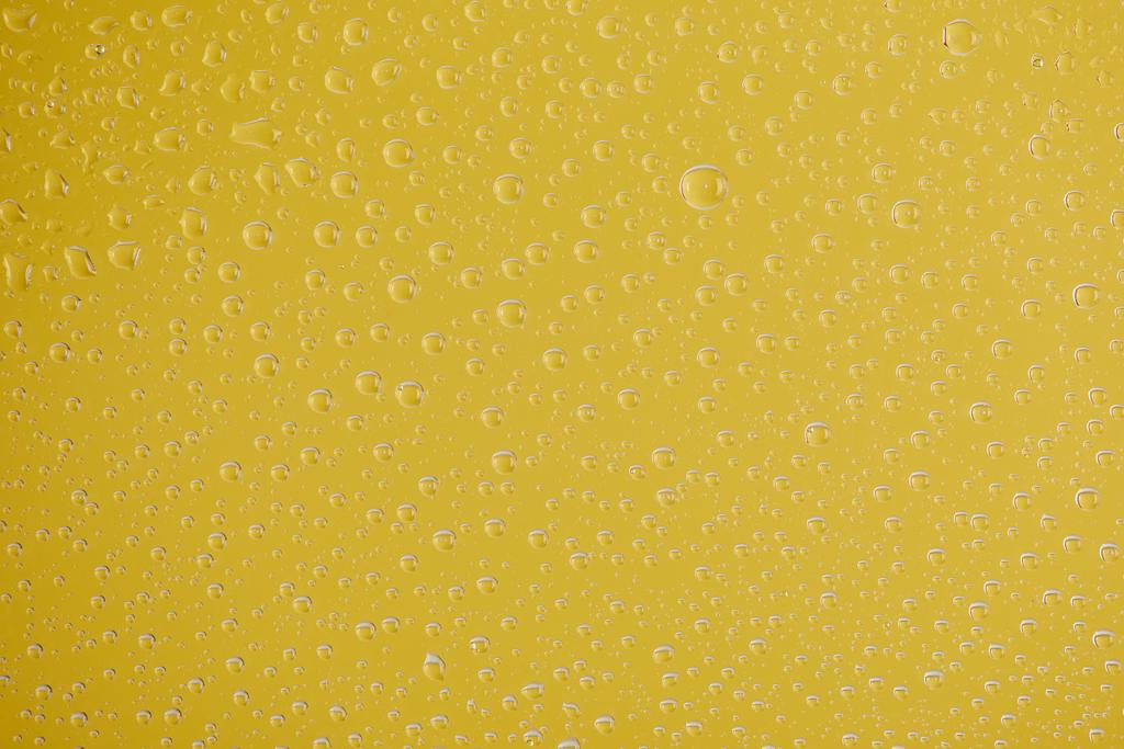 σαφείς διαφανείς σταγόνες νερού σε κίτρινο φόντο - Φωτογραφία, εικόνα