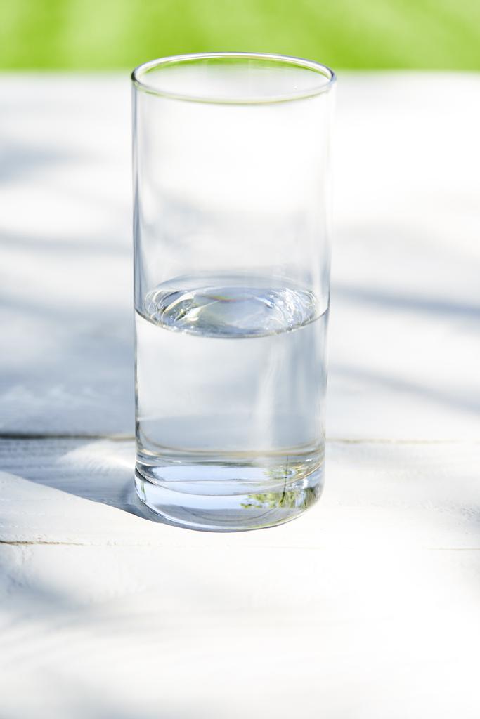Frisches sauberes Wasser in transparentem Glas an sonnigen Tagen auf Holztisch - Foto, Bild