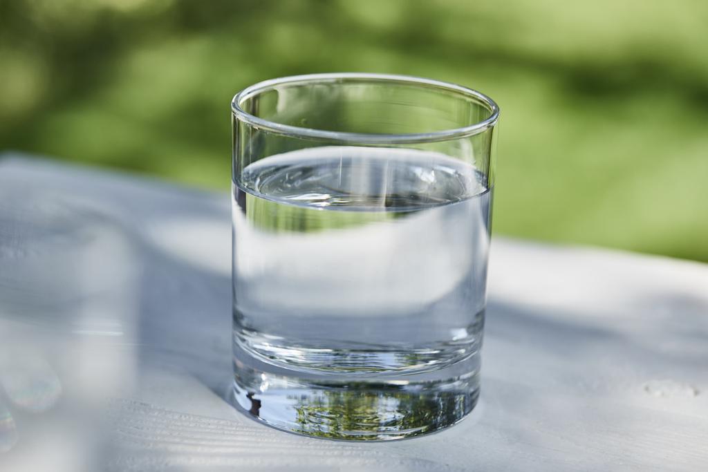 fris schoon water in transparant glas op zonnige dag buiten - Foto, afbeelding