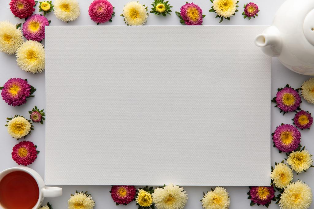 top view of yellow and purple asters and blank paper on white background - Photo, Image