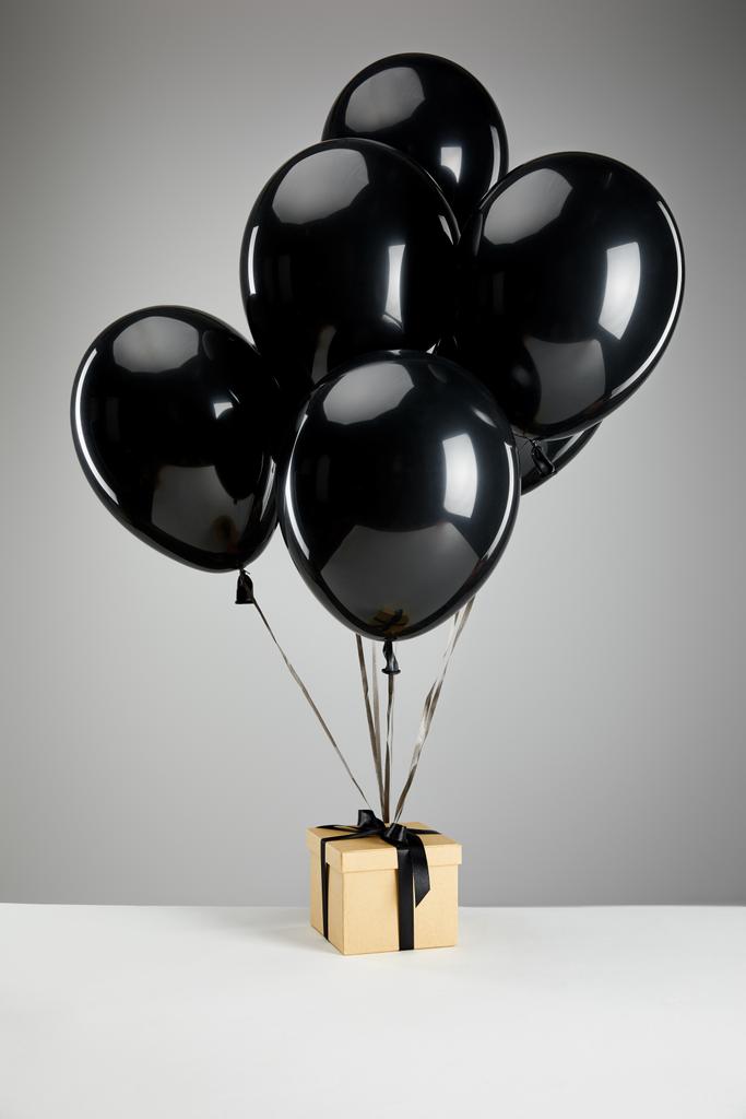 Куча чёрных шариков с подарочной коробкой, изолированных на серой, черной пятничной концепции
 - Фото, изображение