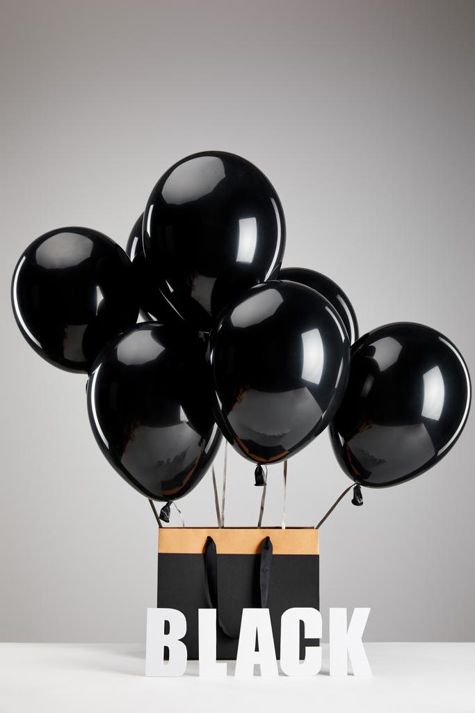 joukko mustia ilmapalloja paperi ostoskassi eristetty harmaa, musta perjantai käsite
 - Valokuva, kuva