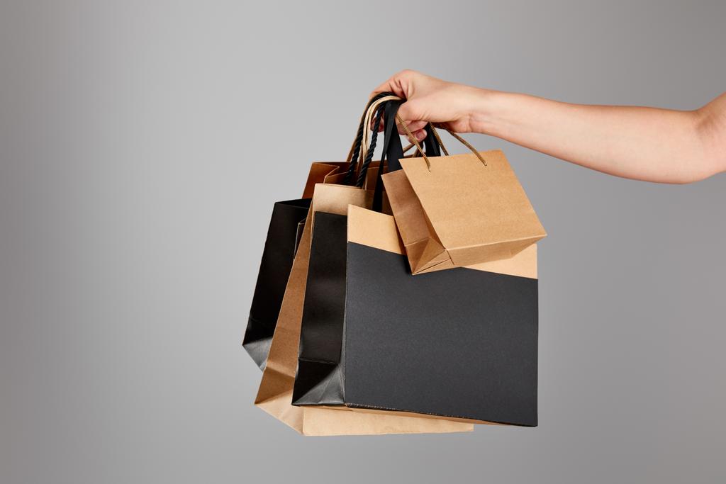 Ausgeschnittene Ansicht einer Frau mit Papiereinkaufstasche isoliert auf grauem, schwarzem Freitag-Konzept - Foto, Bild