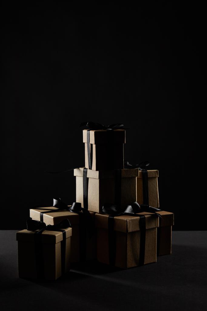 Geschenkboxen aus Karton mit schwarzen Bändern in der Dunkelheit isoliert auf schwarzem, schwarzem Freitag-Konzept - Foto, Bild