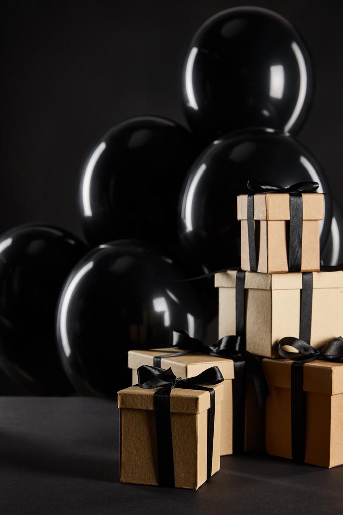 Kara Cuma konseptine izole edilmiş hediye kutularının yanında bir sürü siyah balon. - Fotoğraf, Görsel