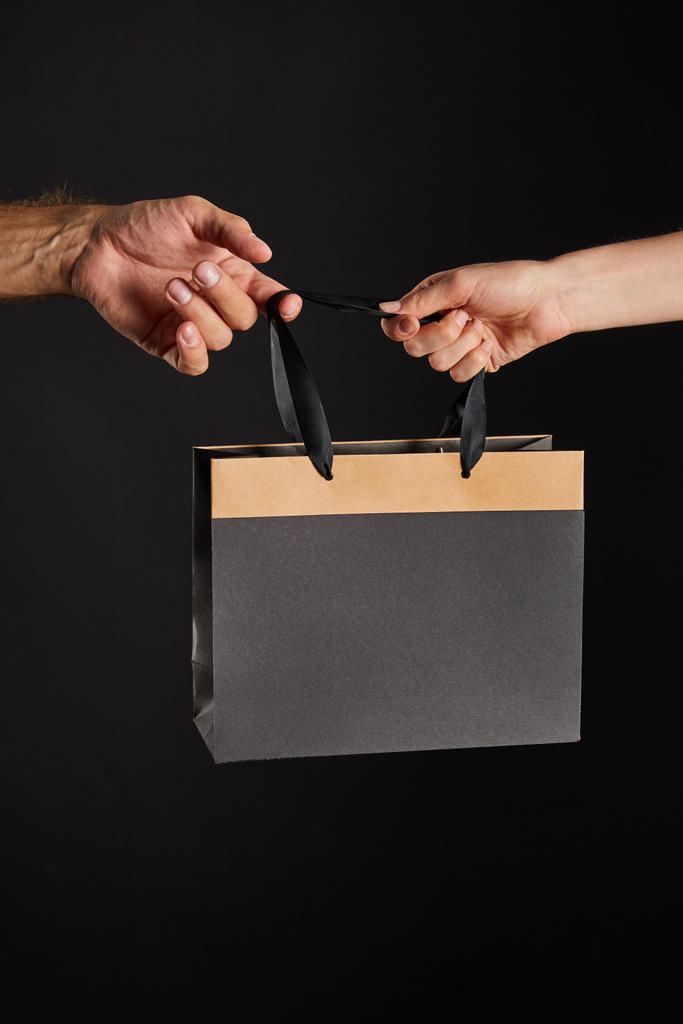 vista ritagliata di donna e uomo in possesso di carta shopping bag isolato su nero, nero concetto Venerdì
 - Foto, immagini