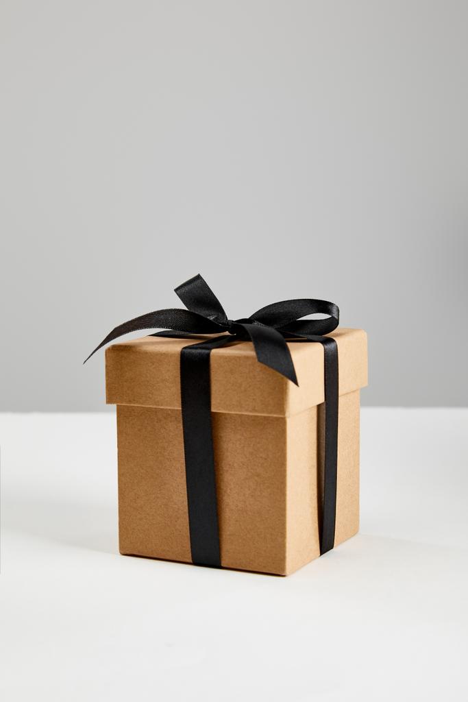 χαρτόκουτο κουτί δώρου με μαύρη κορδέλα σε γκρι, μαύρη Παρασκευή έννοια - Φωτογραφία, εικόνα