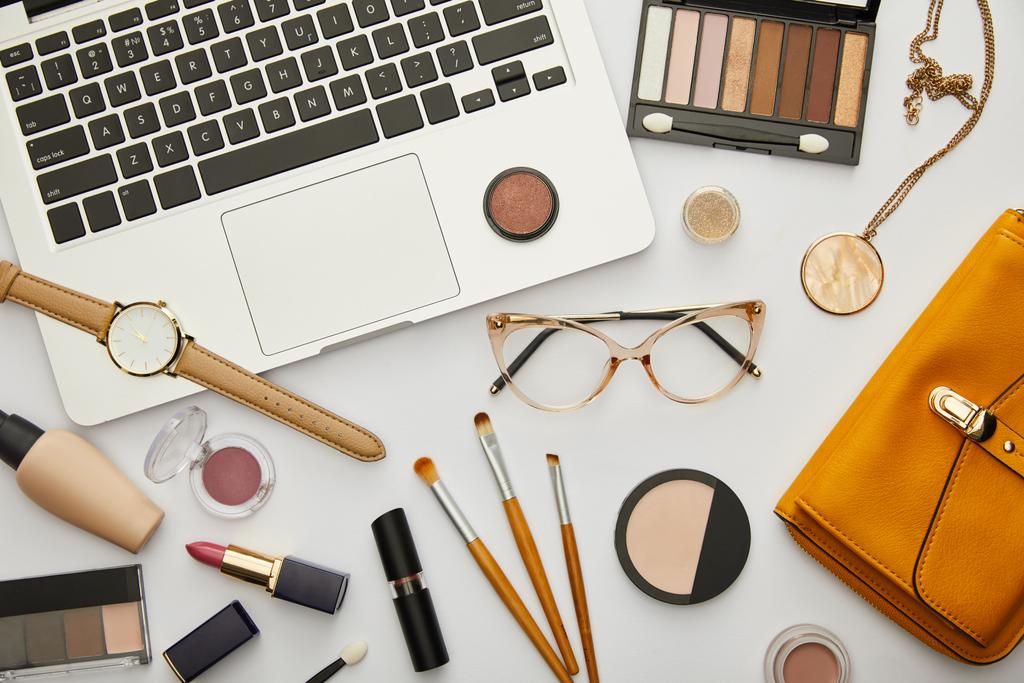 top view laptop közelében sárga táska, szemüveg és dekoratív kozmetikumok elszigetelt szürke  - Fotó, kép
