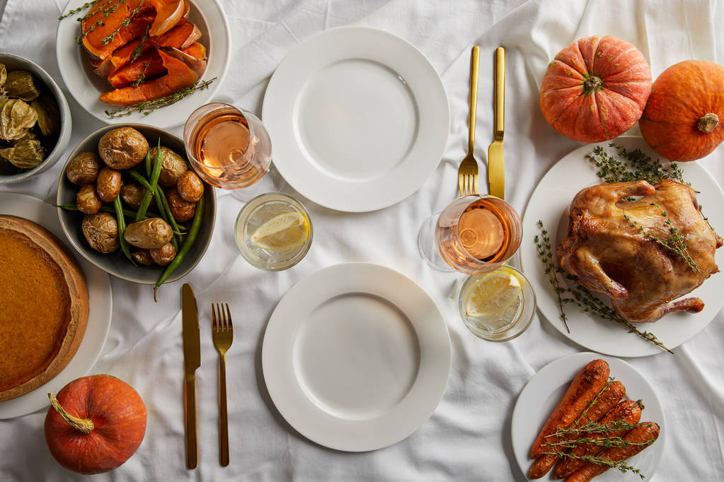 top view of thanksgiving dinner with grilled turkey, baked vegetables and whole pumpkins on white tablecloth - Photo, Image