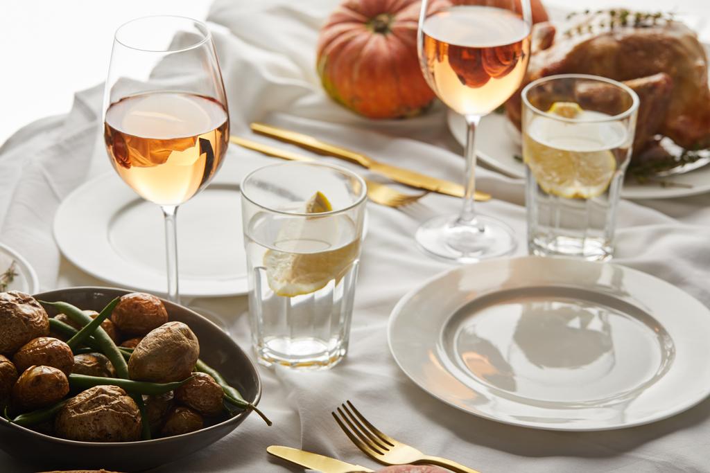 Juhlallinen kiitospäivän illallinen paistettujen vihannesten, ruusuviinilasien ja kokonaisten kurpitsojen kanssa valkoisella marmoripöydällä
 - Valokuva, kuva