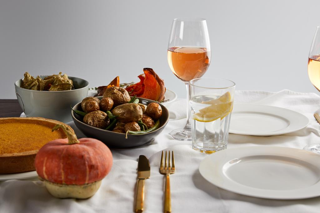 verduras al horno, pastel de calabaza y calabaza entera cerca de vasos con vino de rosas y agua de limón aislados en gris
 - Foto, imagen