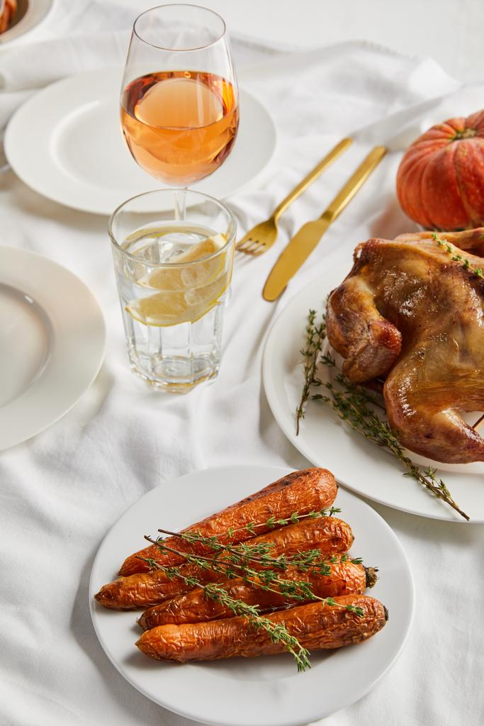 peru grelhado e cenoura perto de copos com vinho rosa e água de limão na toalha de mesa branca
 - Foto, Imagem