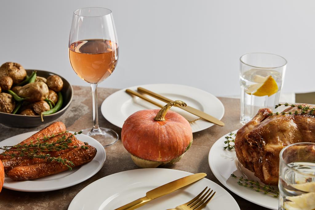 Δείπνο Ευχαριστιών με ψητά λαχανικά, ψητή γαλοπούλα και ποτήρια με ροζέ κρασί και λεμονάτο νερό σε γκρι χρώμα - Φωτογραφία, εικόνα