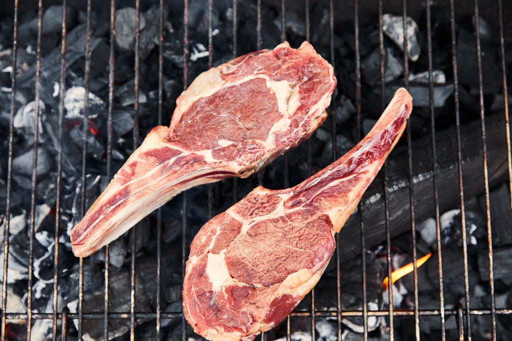 bovenaanzicht van rauw vlees grillen op barbecue rooster buiten  - Foto, afbeelding