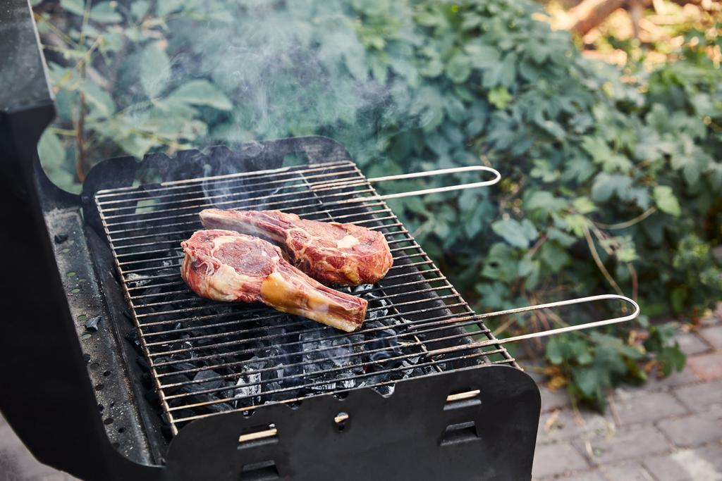carne cruda grigliata su griglia barbecue e pezzi di carbone all'esterno
  - Foto, immagini