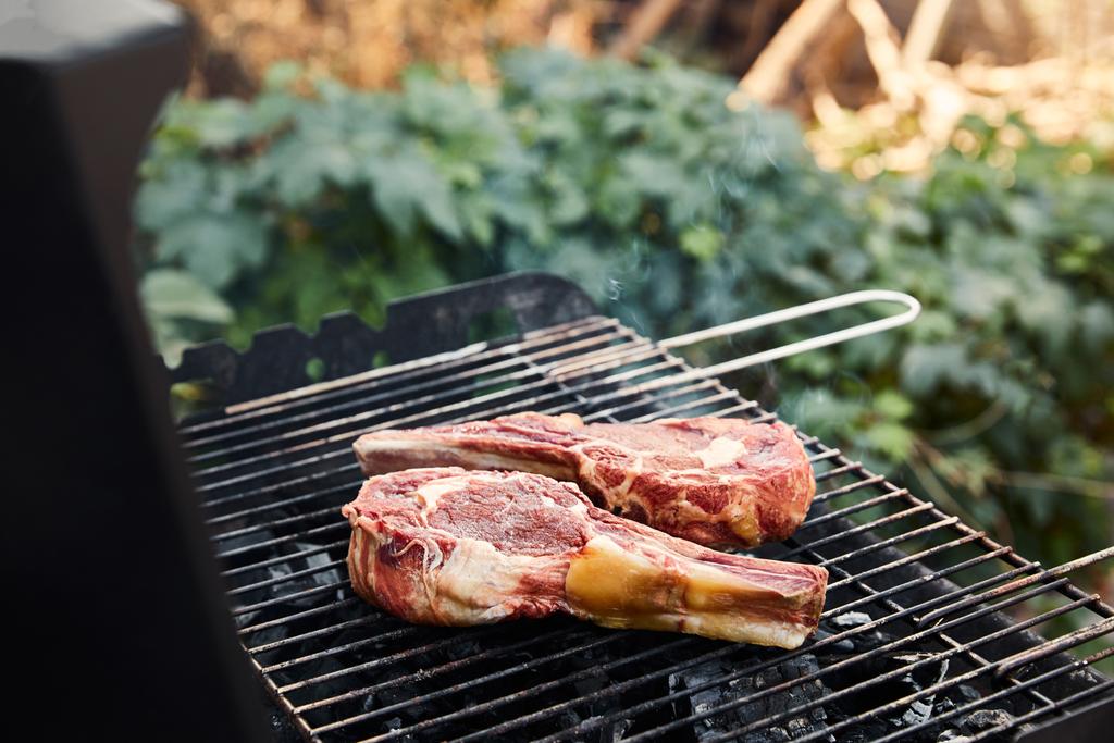 a nyers hús grillezésének szelektív fókusza a grillrácson kívül  - Fotó, kép