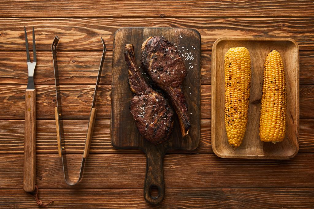 kiváló kilátás a húsra, kukoricára vágódeszkákon és grill szerszámokra   - Fotó, kép