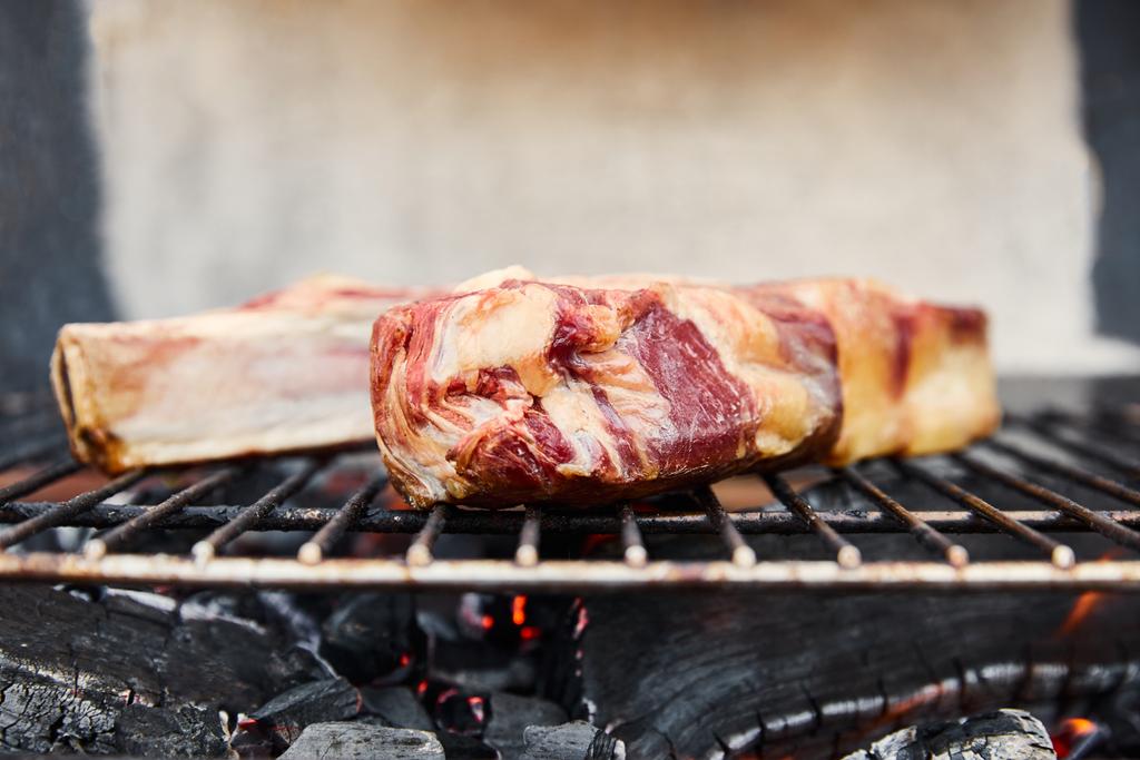 rohes Fleisch grillen auf Grillrost und Kohlestücke draußen  - Foto, Bild