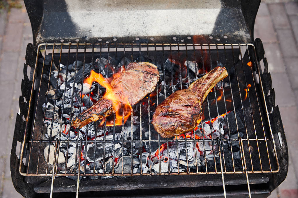 vista dall'alto di carne grigliate sulla griglia barbecue e pezzi di carbone al di fuori
  - Foto, immagini
