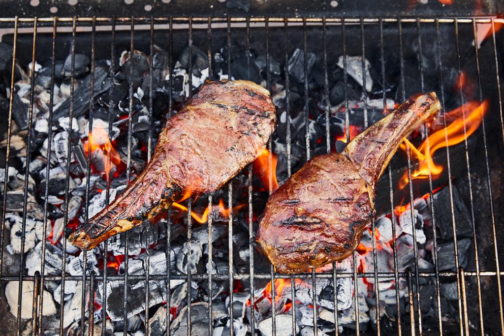 top view of meat grilling on barbecue grid and coal pieces outside  - Photo, Image