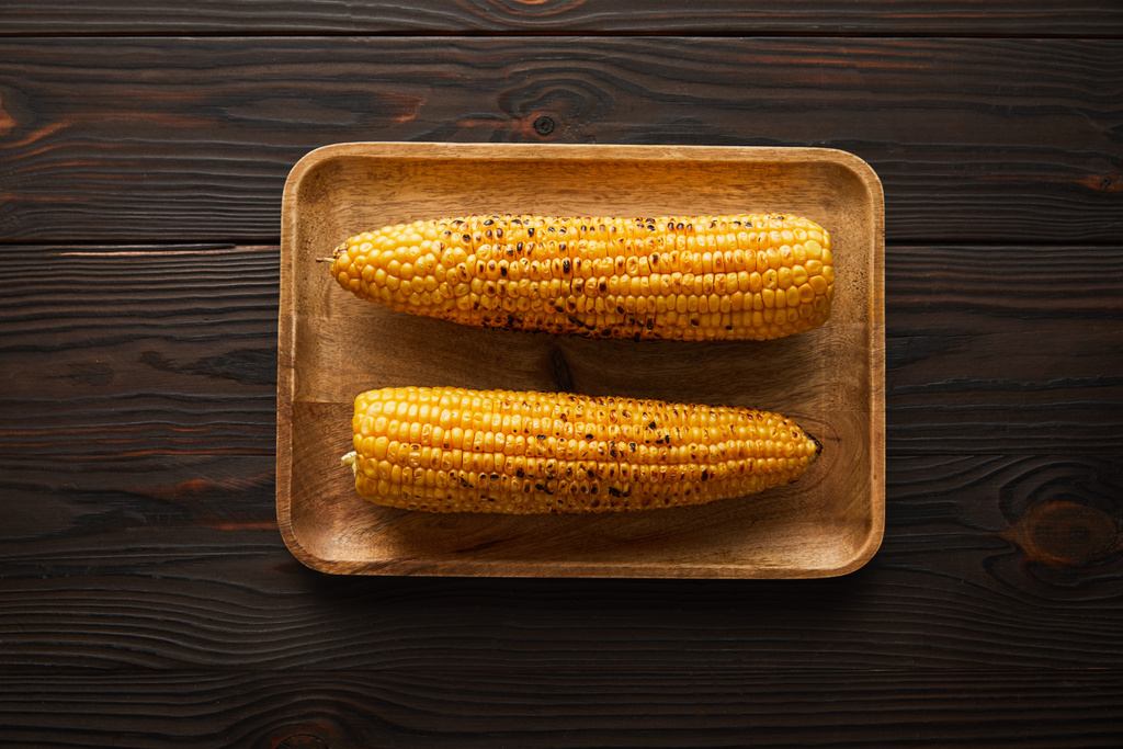 вид сверху на вкусную и органическую кукурузу на деревянной тарелке
  - Фото, изображение