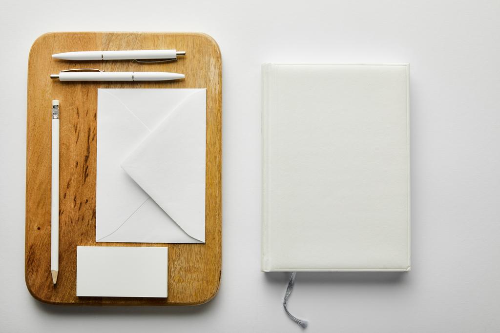 верхний вид конверта, визитной карточки, карандаша и ручек на деревянной доске и ноутбука
 - Фото, изображение