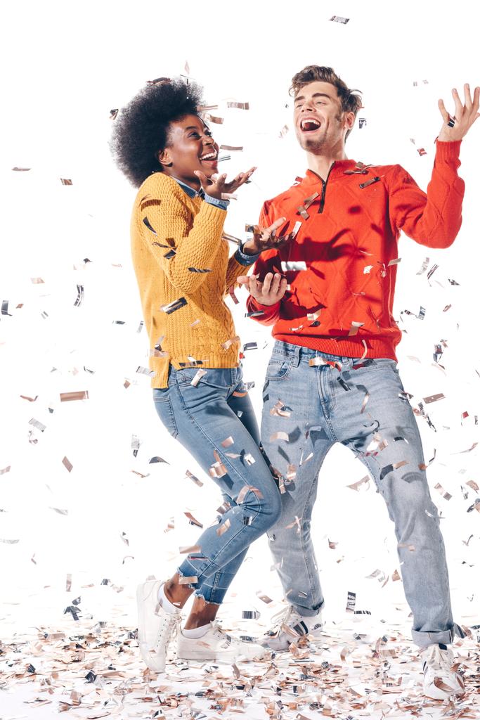 feliz pareja multiétnica bailando con confeti, aislado en blanco
  - Foto, Imagen