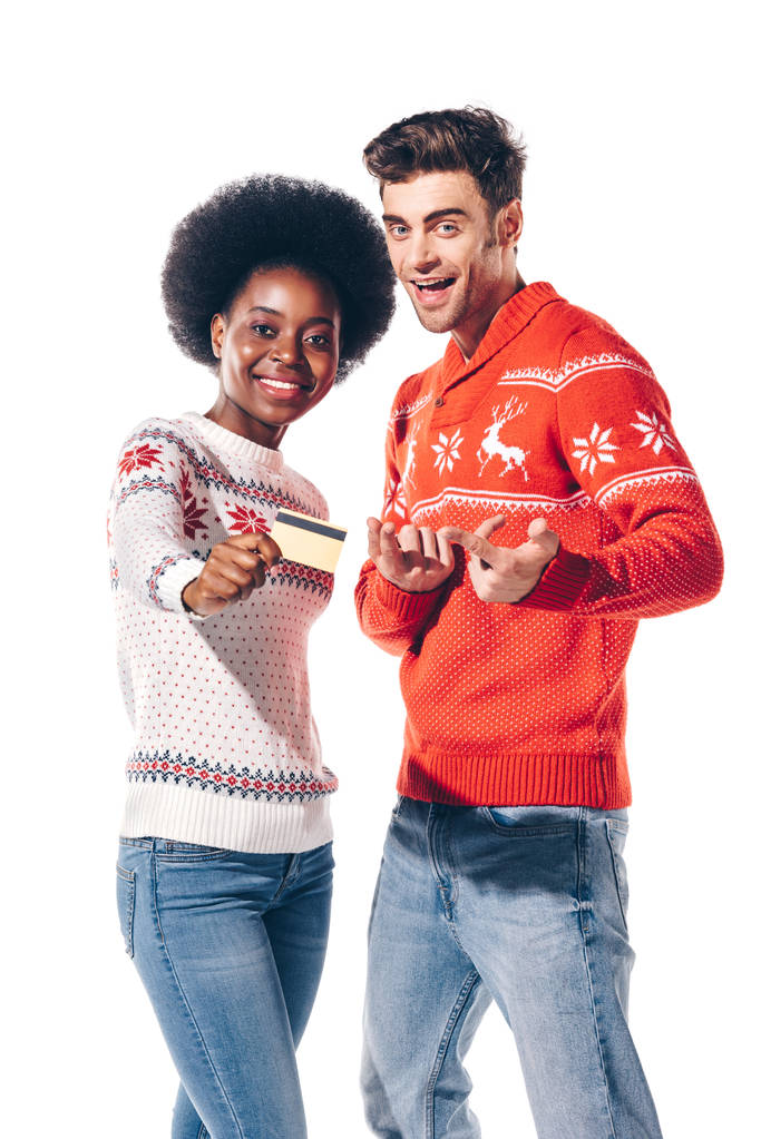 happy multicultural couple in winter sweaters holding credit card, isolated on white - Photo, Image
