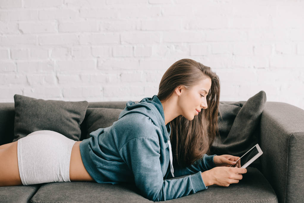 hermosa mujer en bragas usando tableta digital mientras está acostado en el sofá
 - Foto, imagen